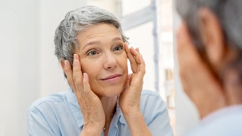 Health: Retinoids: woman looking at wrinkles in the mirror-1044153532