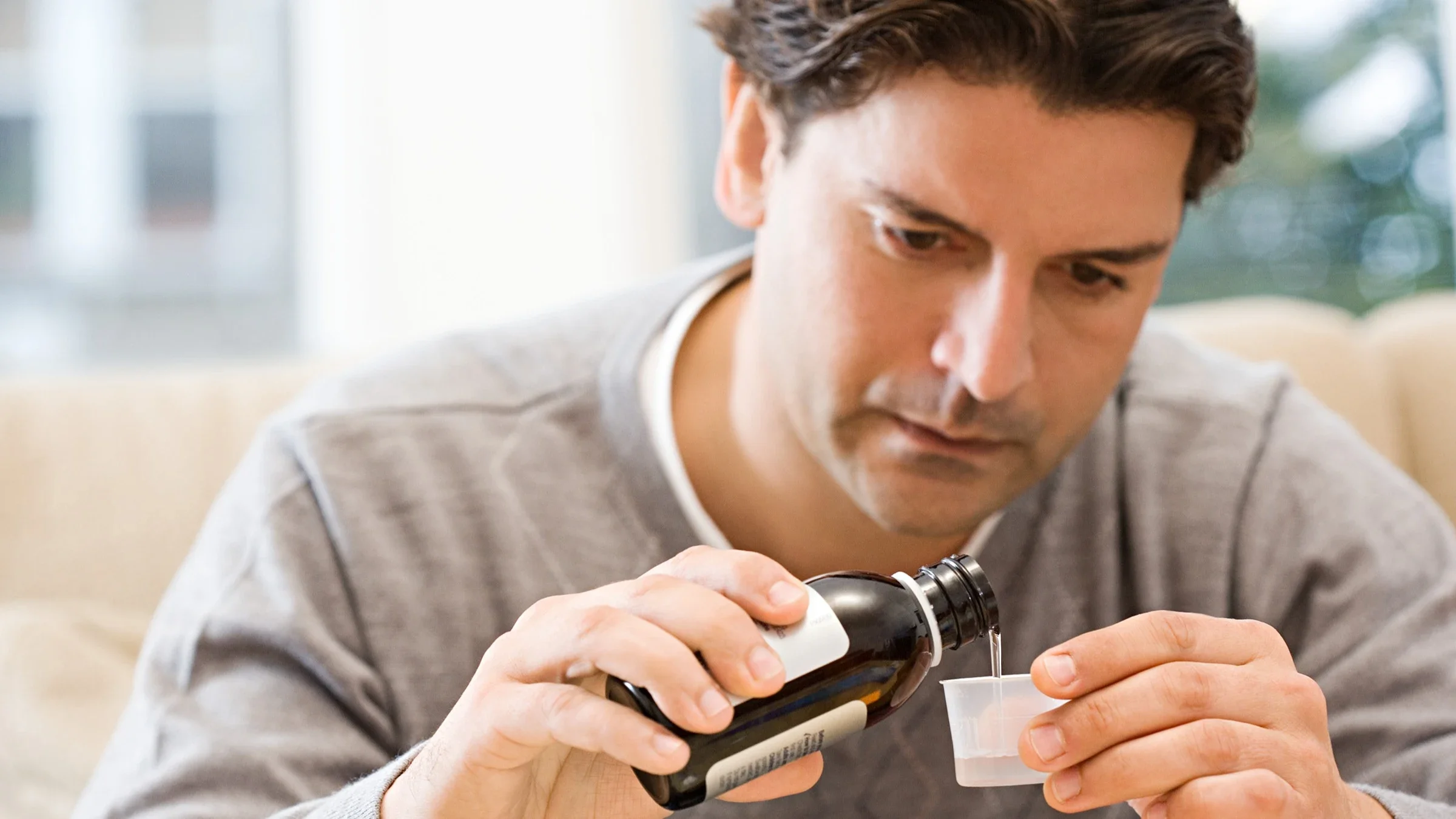 Close-up on a man pouring liquid medication into a measuring cup. He has a very concentrated look on his face.
Image Source/Stockbyte via Getty Images
