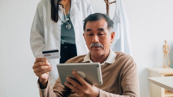 Patient advocacy: ER for non-emergencies: doctor behind patient making contactless tablet payment 1390980086