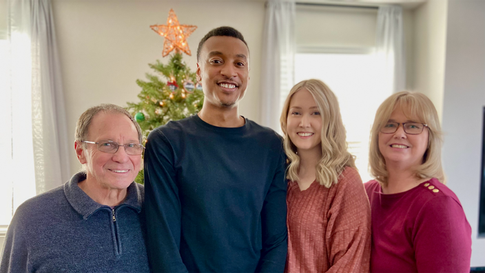 Samantha Boothe is pictured in front of a Christmas tree with her husband and parents.