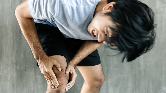 A man is holding his knee in pain.