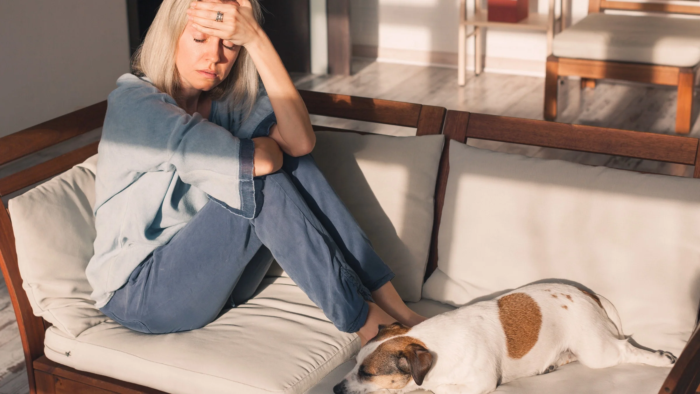 A stressed person on their couch, with their dog.