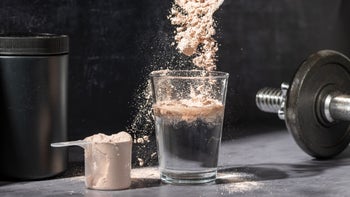 Supplements and herbs: closeup pouring chocolate protein powder in glass 2162409255