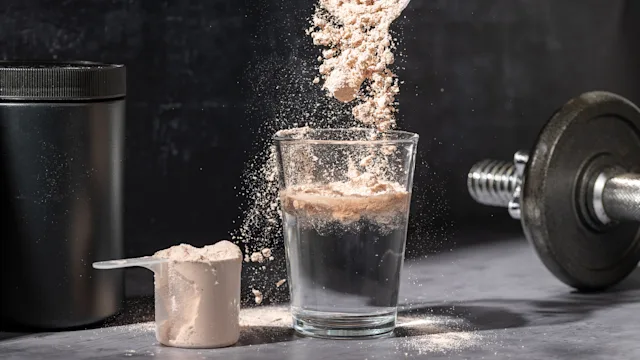Supplements and herbs: closeup pouring chocolate protein powder in glass 2162409255