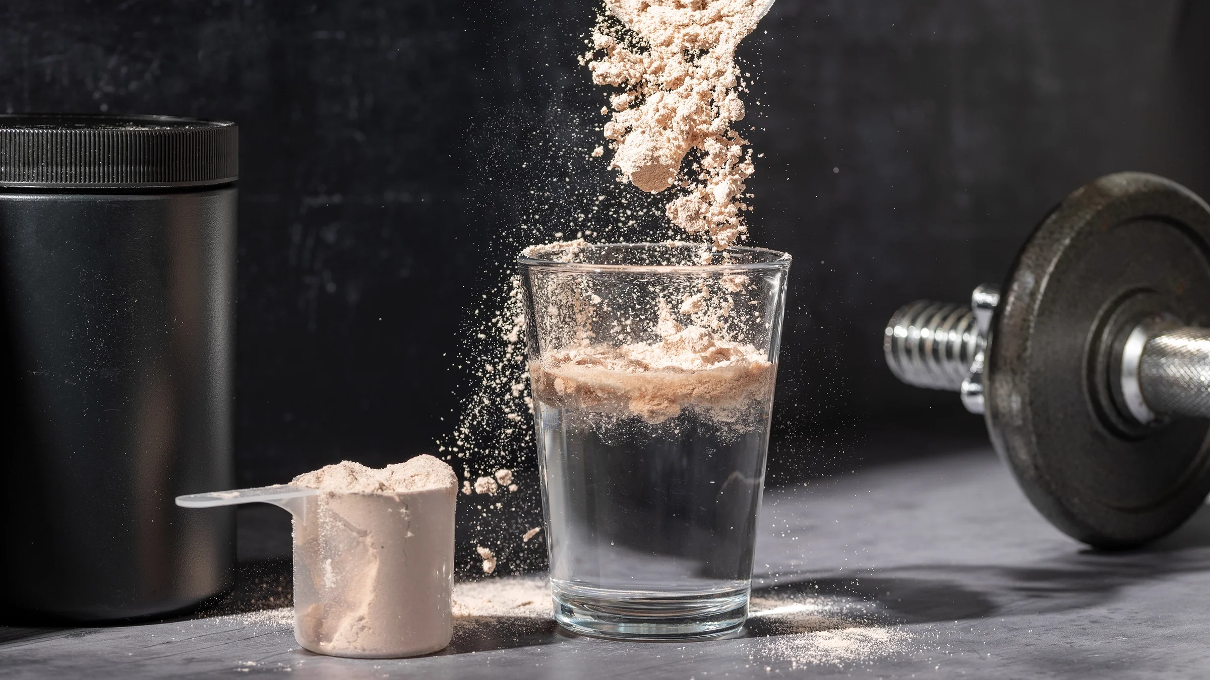 Close-up pouring chocolate protein powder into a glass.
