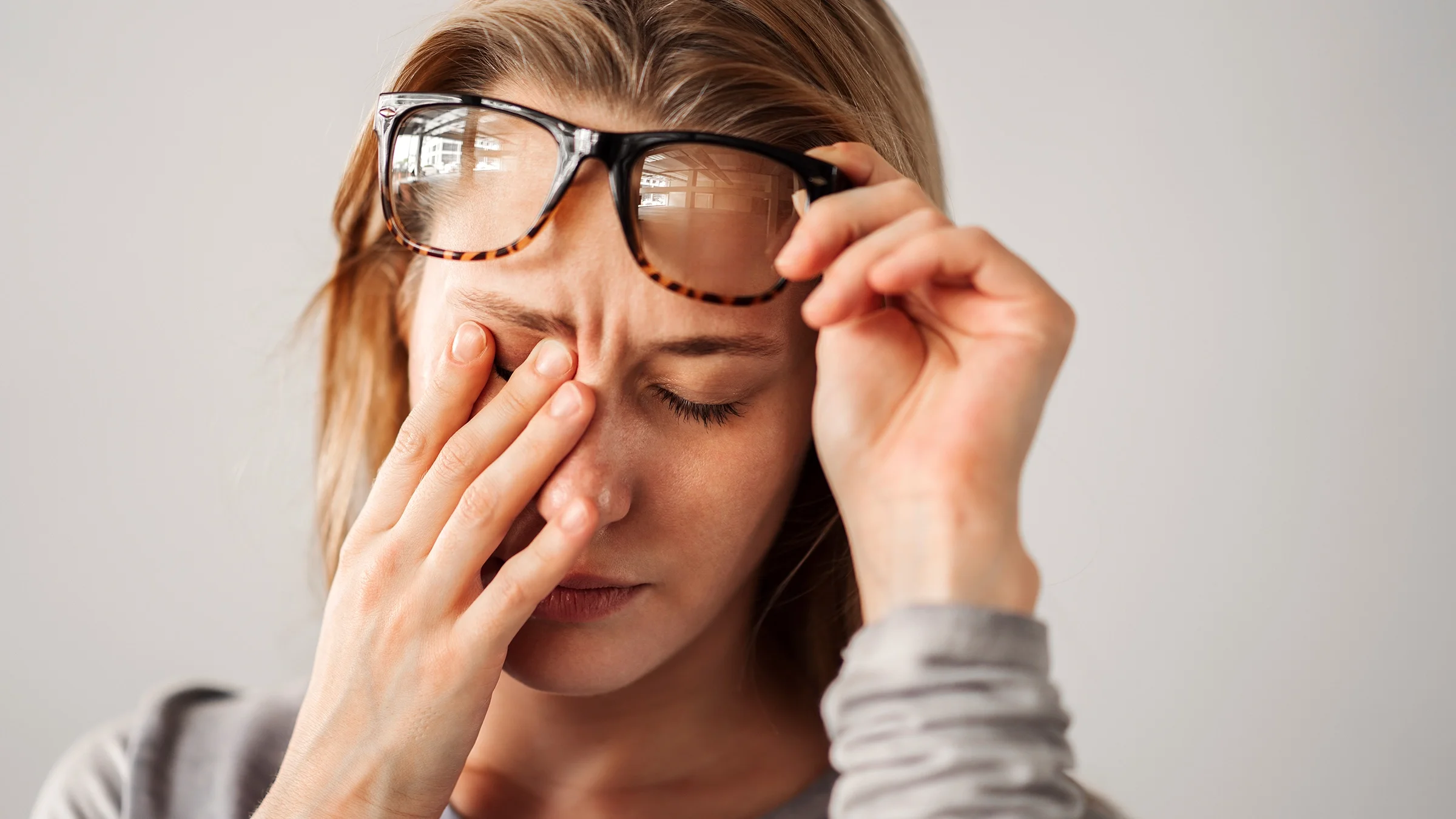 A woman with eye pain is grimacing.