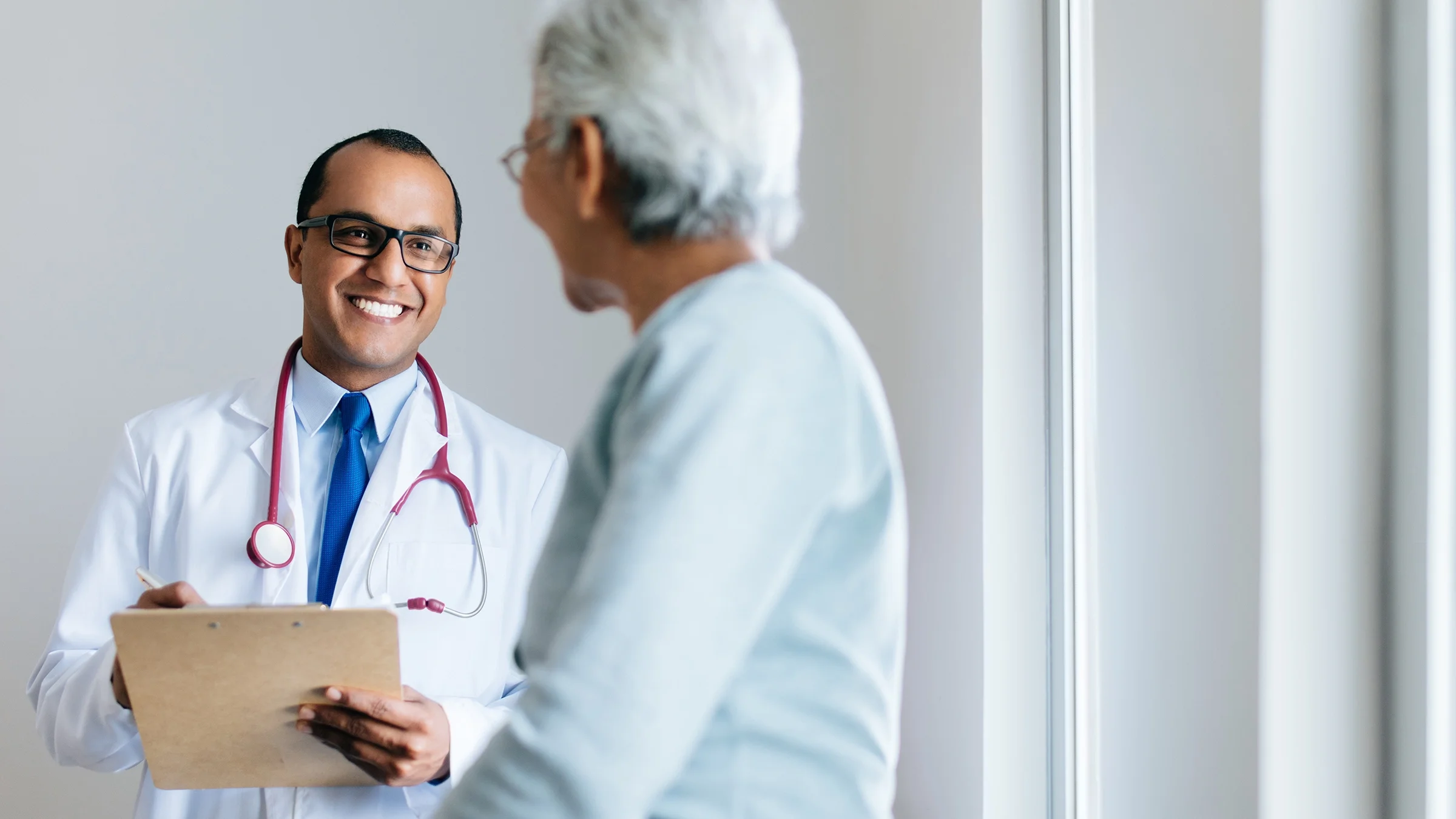 Smiling doctor helping patient in the exam room.