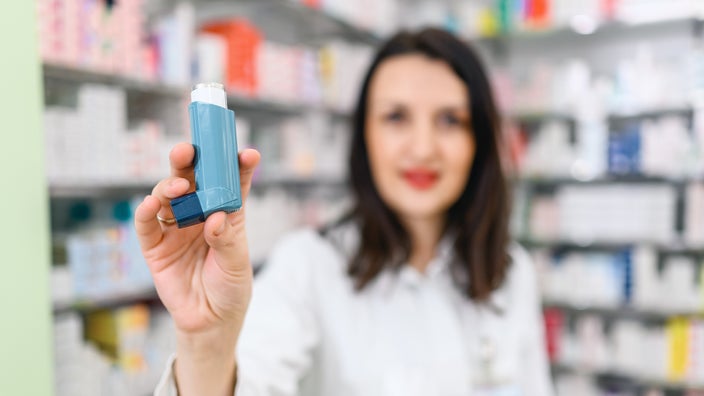 Close-up image of an asthma inhaler being held by a pharmacist.
