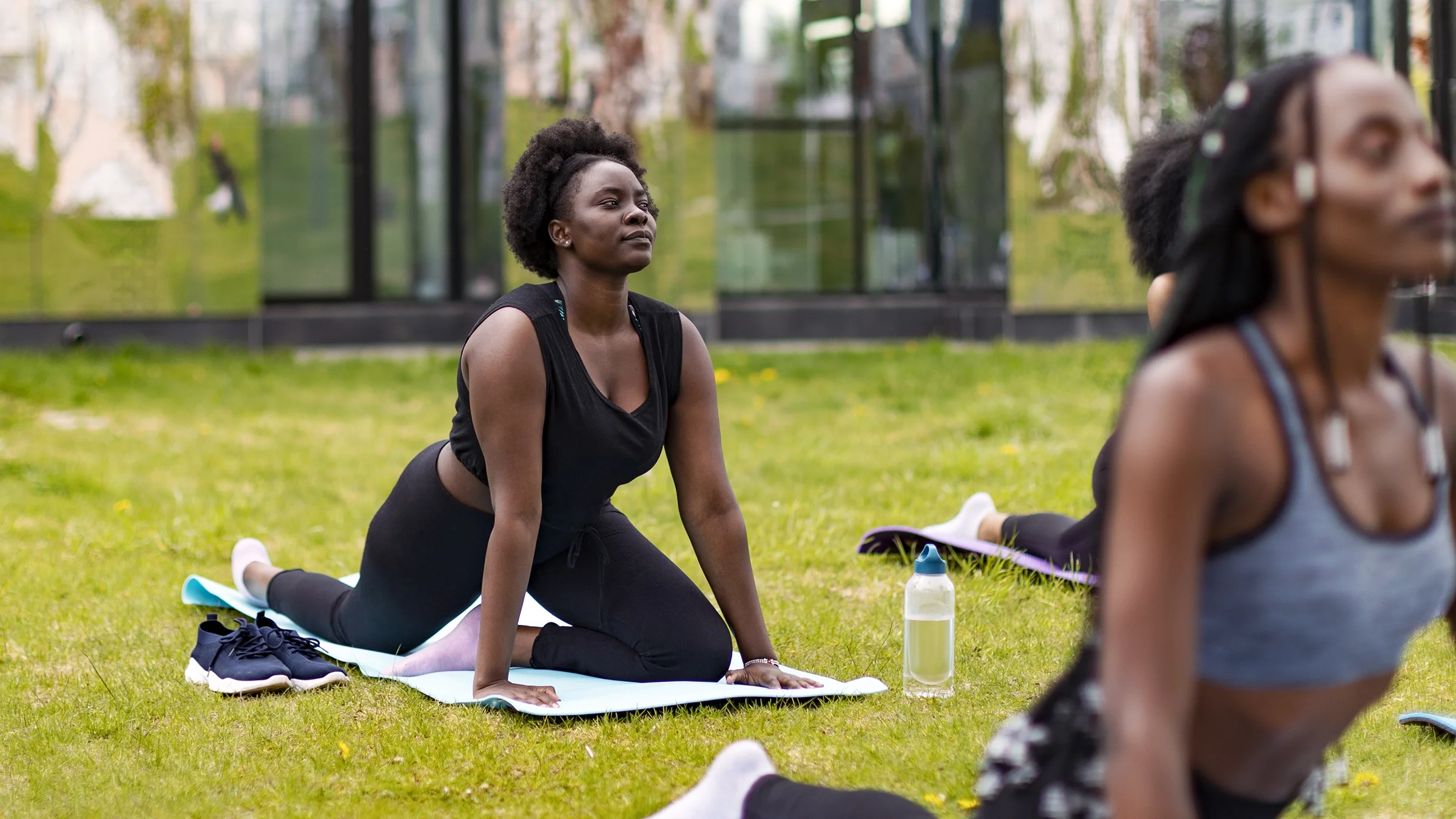 A woman is stretching in a pigeon pose outdoors.