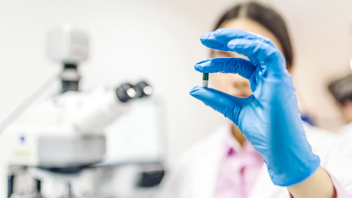 A scientist examining a pill. 
