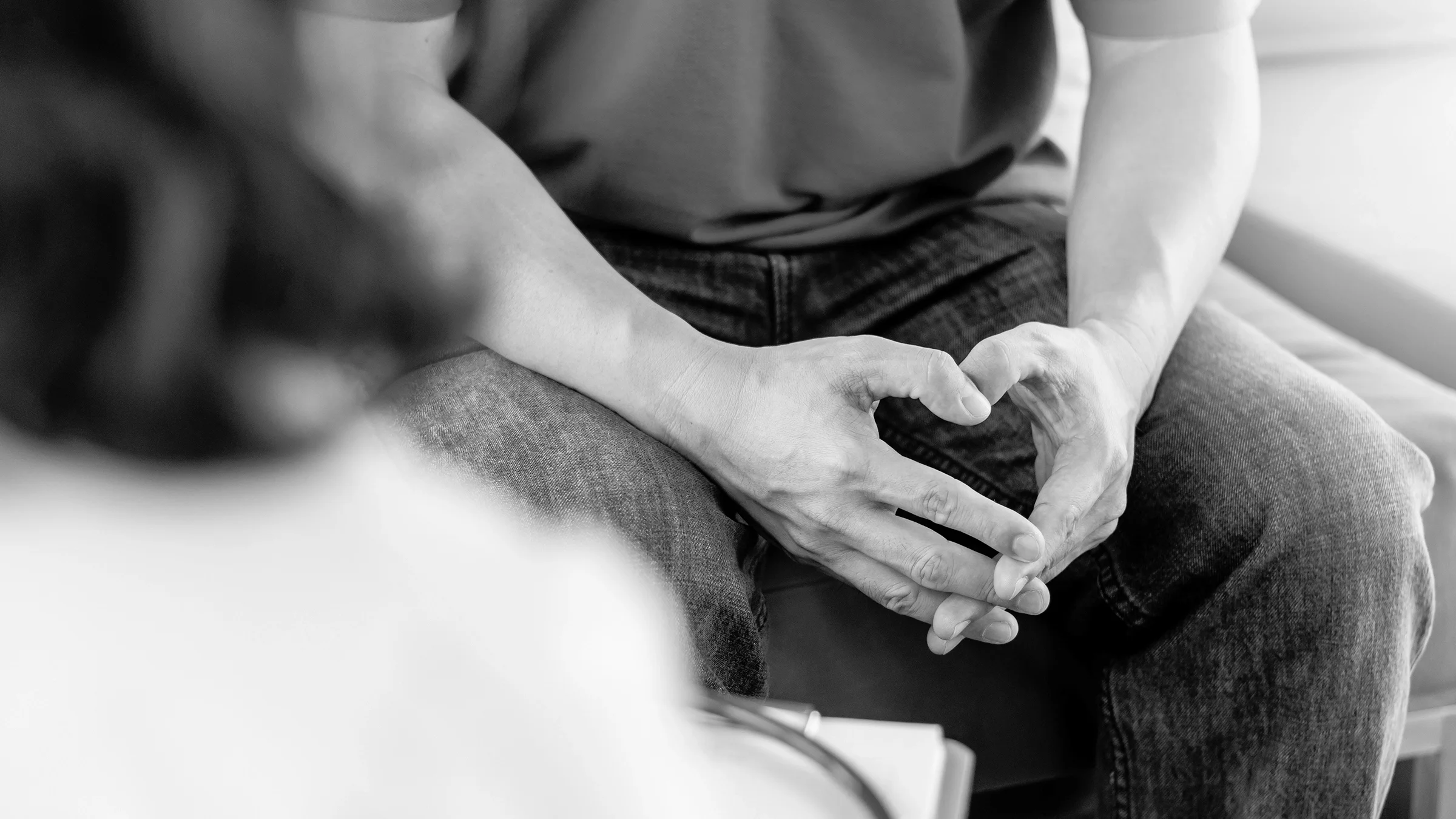 Cropped shot of a man's hands in his lap as he talks with his doctor.