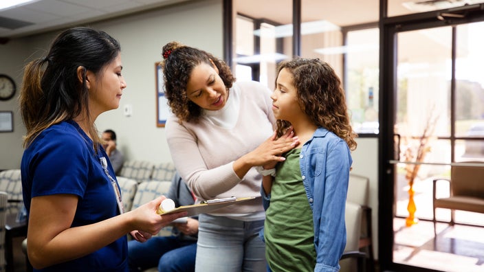 Adult explaining child's symptoms to a nurse.
