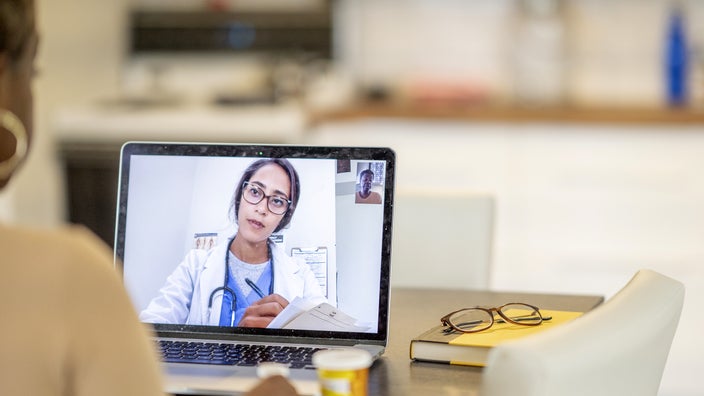 A woman is speaking to a doctor during a telehealth appointment.