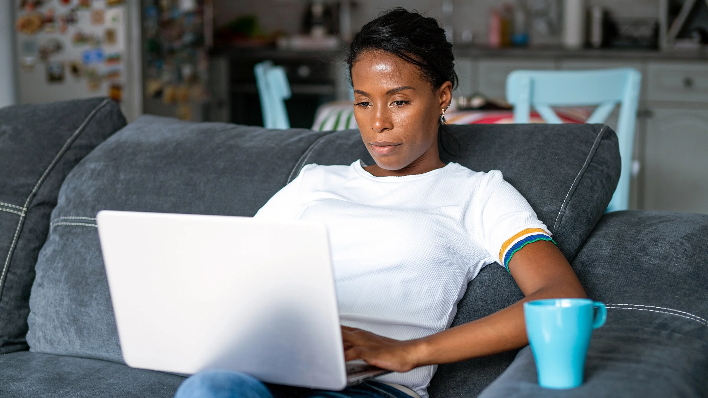 A woman is doing research on her laptop while drinking a cup of coffee.