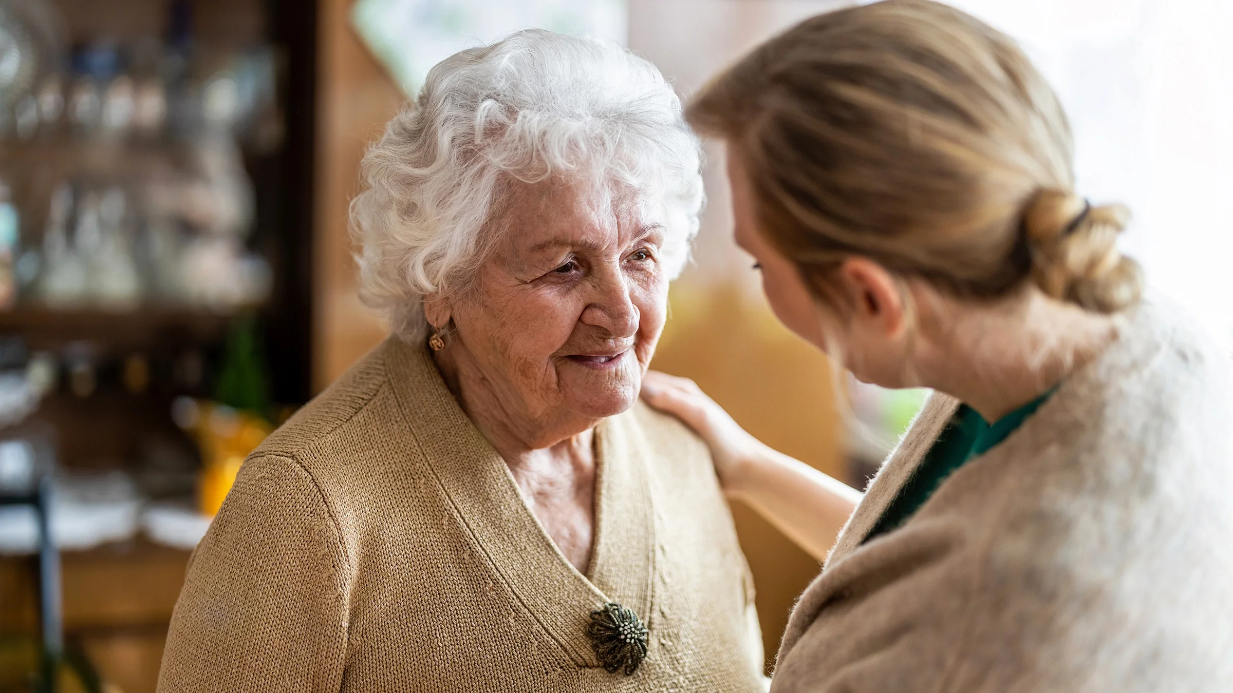 Nurse consoling an elderly woman at home.
