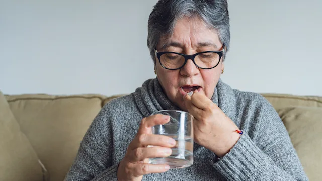 Pharmacy: woman taking medicine at home 1318743565