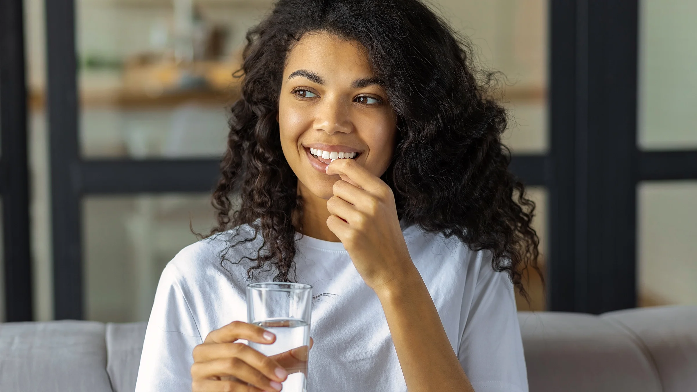 A woman takes an oral medication.