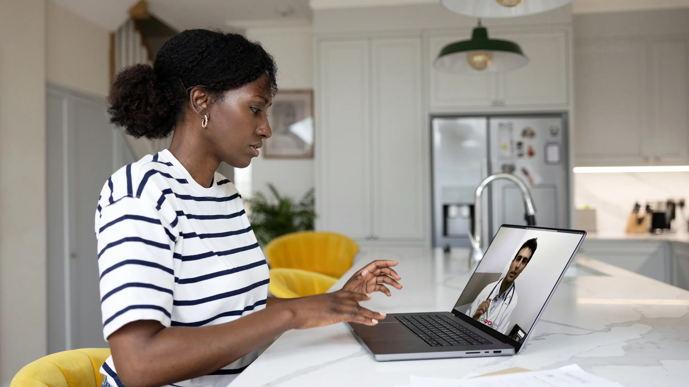 A woman at home talks to her doctor on a video call.