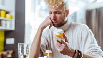 Medications: man with prescription pill bottle 1440077260