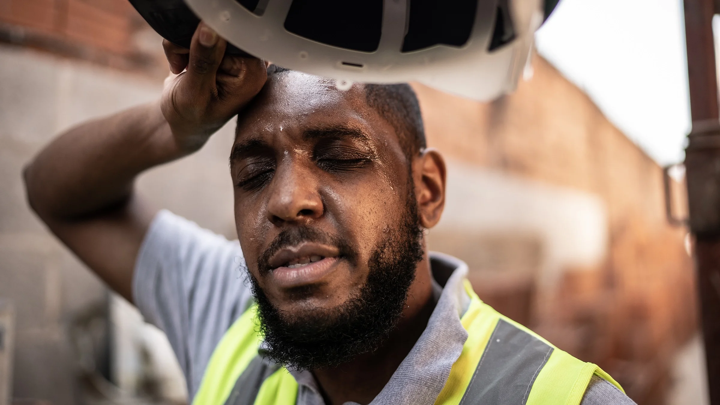 Exhausted construction worker wiping forehead sweat.