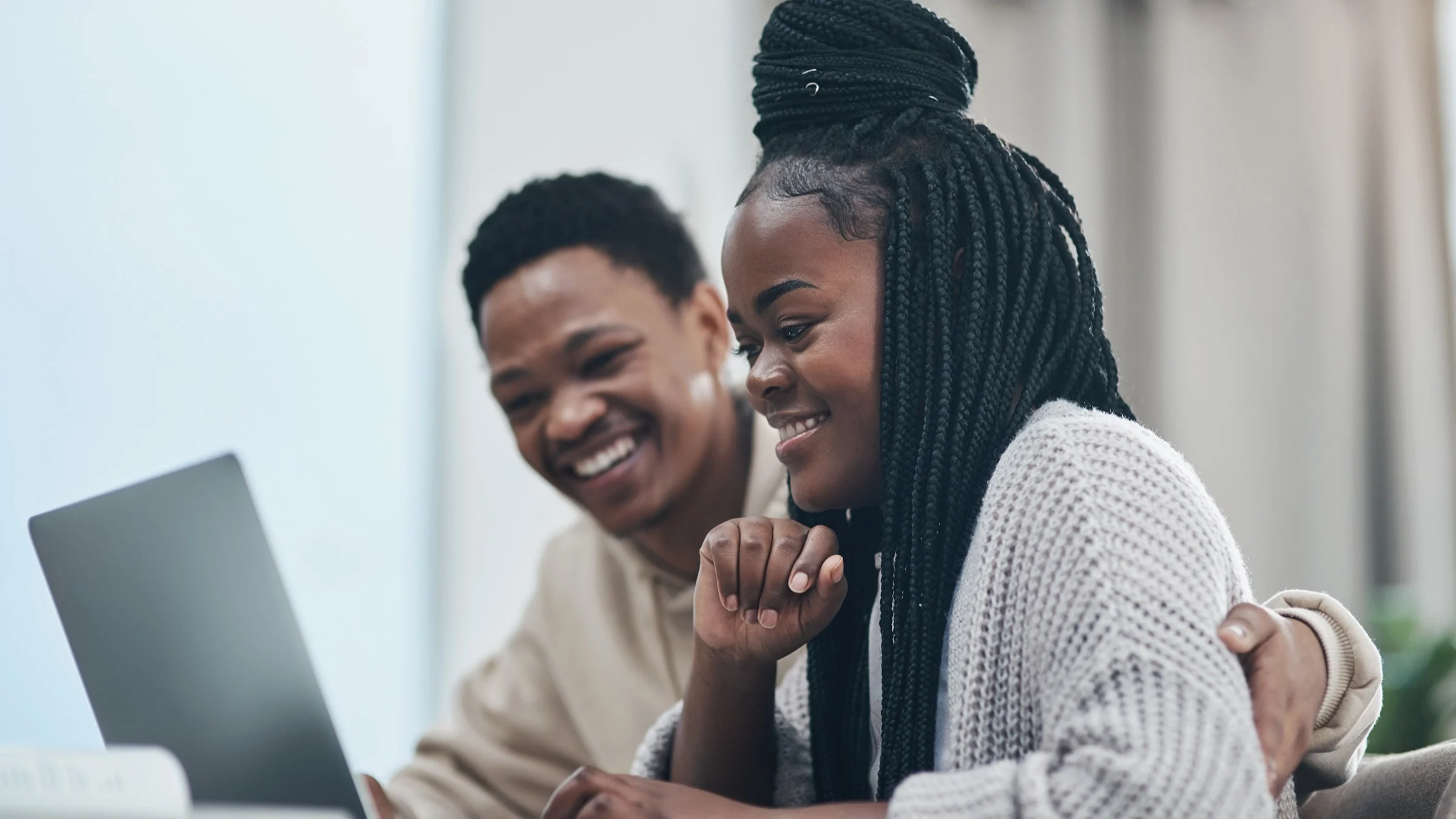 Two students working together at a laptop looking up something online.