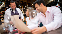 A couple ordering from the menu at a wine bar. 
andresr/E+ via Getty Images 