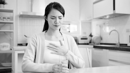 Black and white image of a person with their hand on the chest as if they are experiencing heartburn.
PonyWang/iStock via Getty Images
