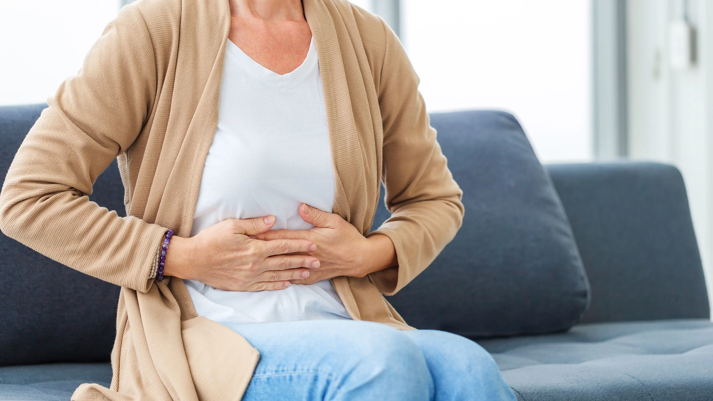 A woman with indigestion clutches her stomach in discomfort.