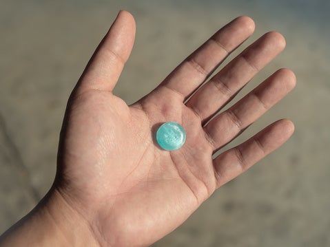 Close-up of a blue cough drop in a person's hand.