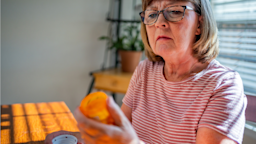 A woman reads the side of a Rx bottle in her kitchen.
grandriver/E+ via Getty Images 