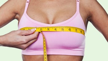 Health: Womens health: women in pink sports bra using tape measure-120972352