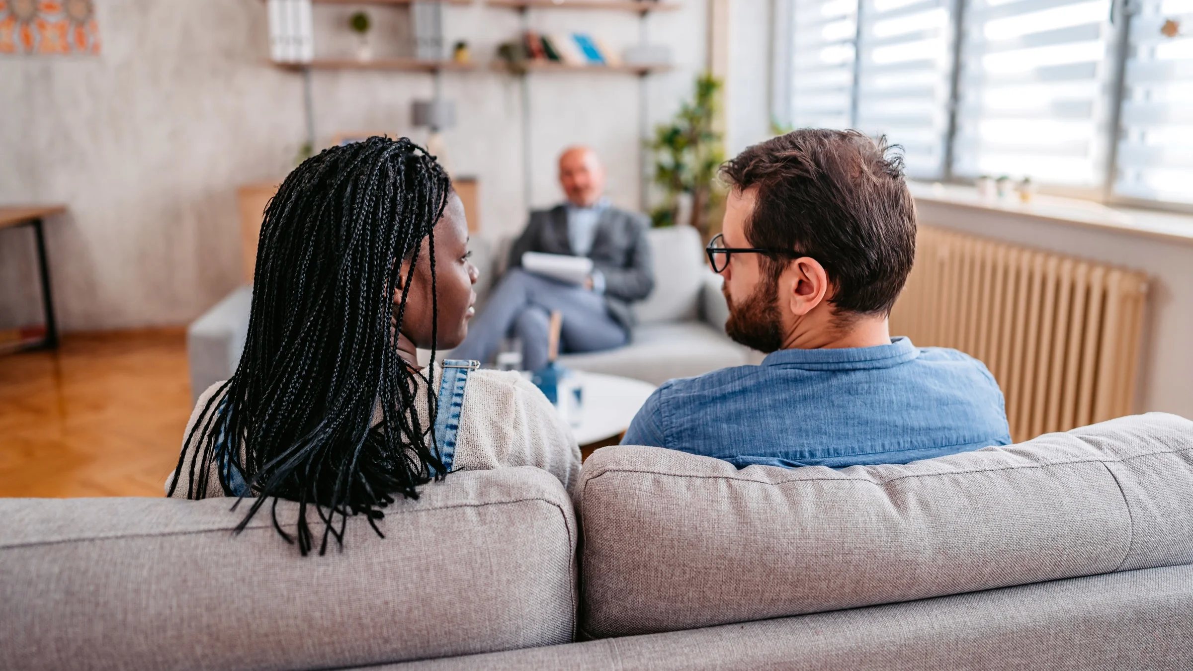 A couple sitting on a couch in counselor's office. 
