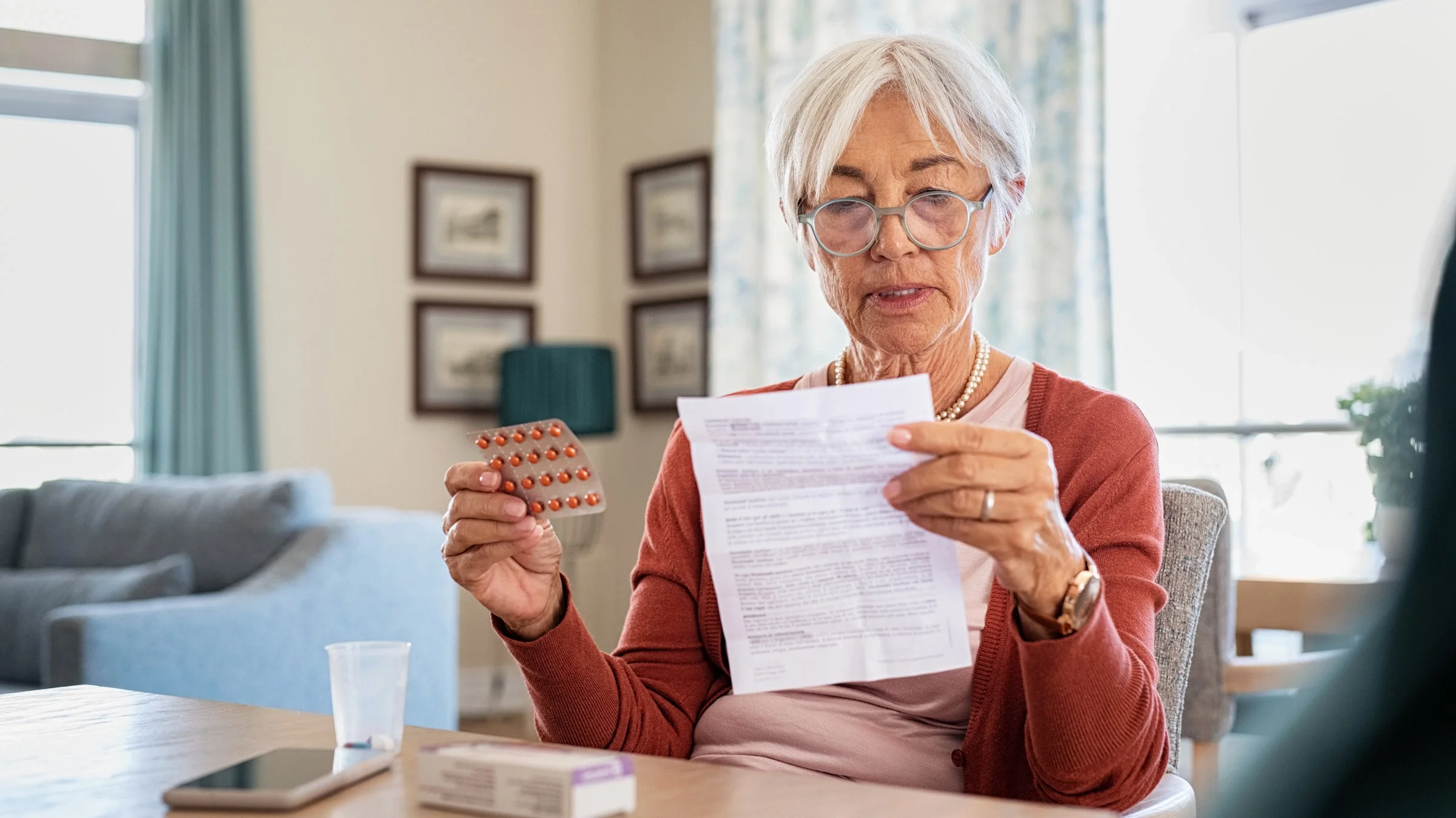 Senior woman reading drug information while holding a blister pack of medication