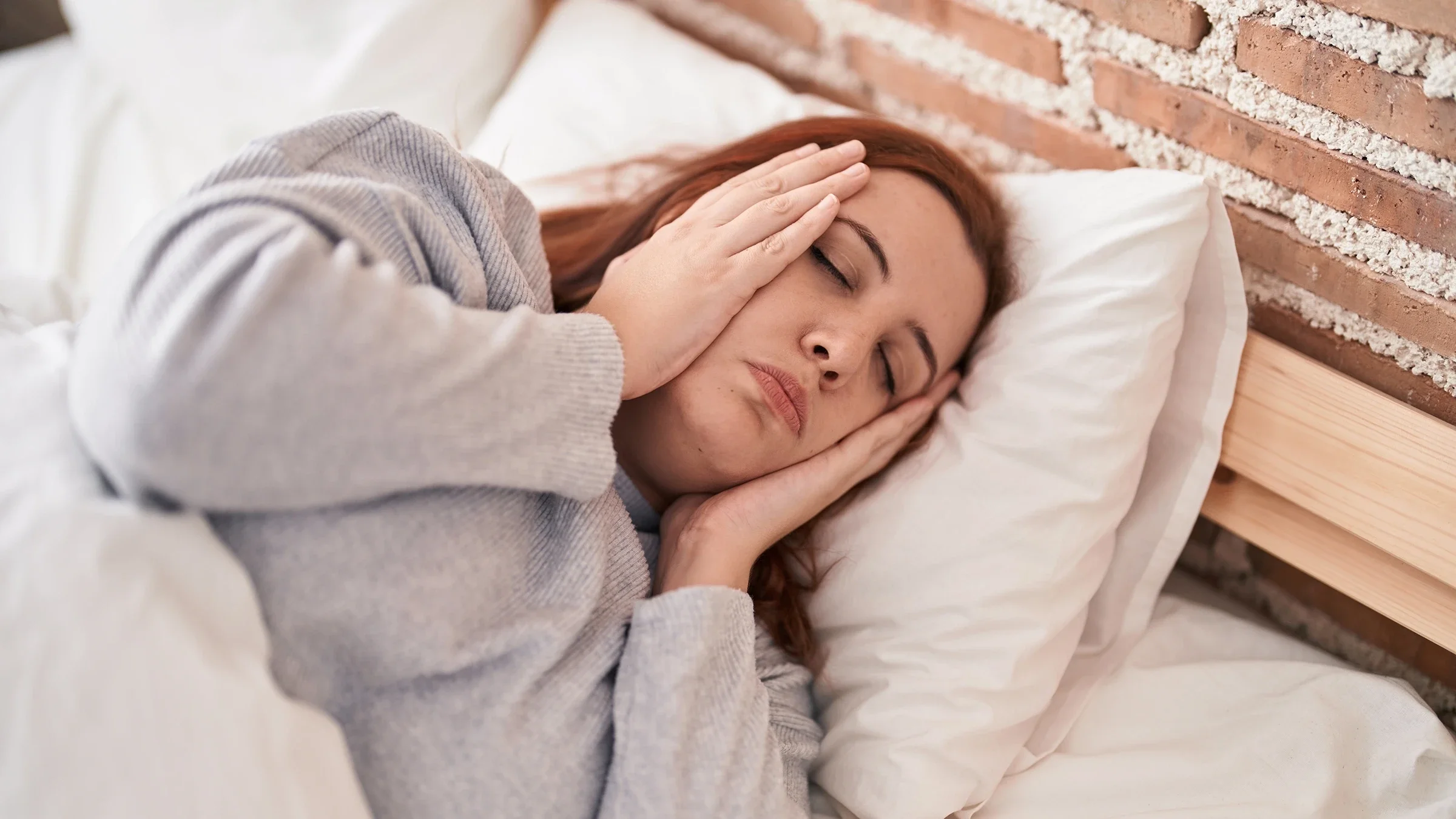 Woman lying in bed, looking stressed.