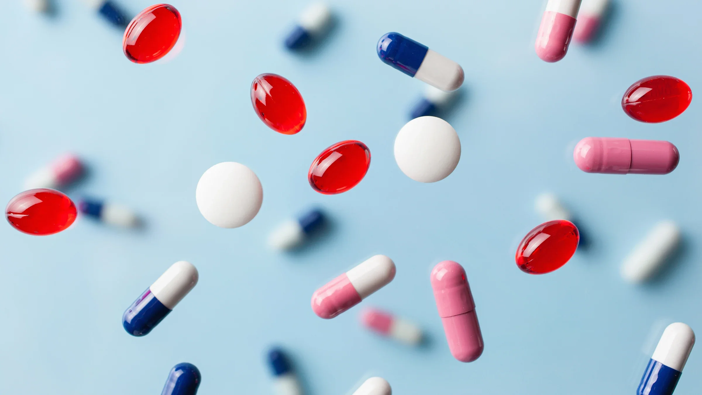 Various types of colorful pills raining down on a light-blue background.
OlgaMiltsova/iStock via Getty Images