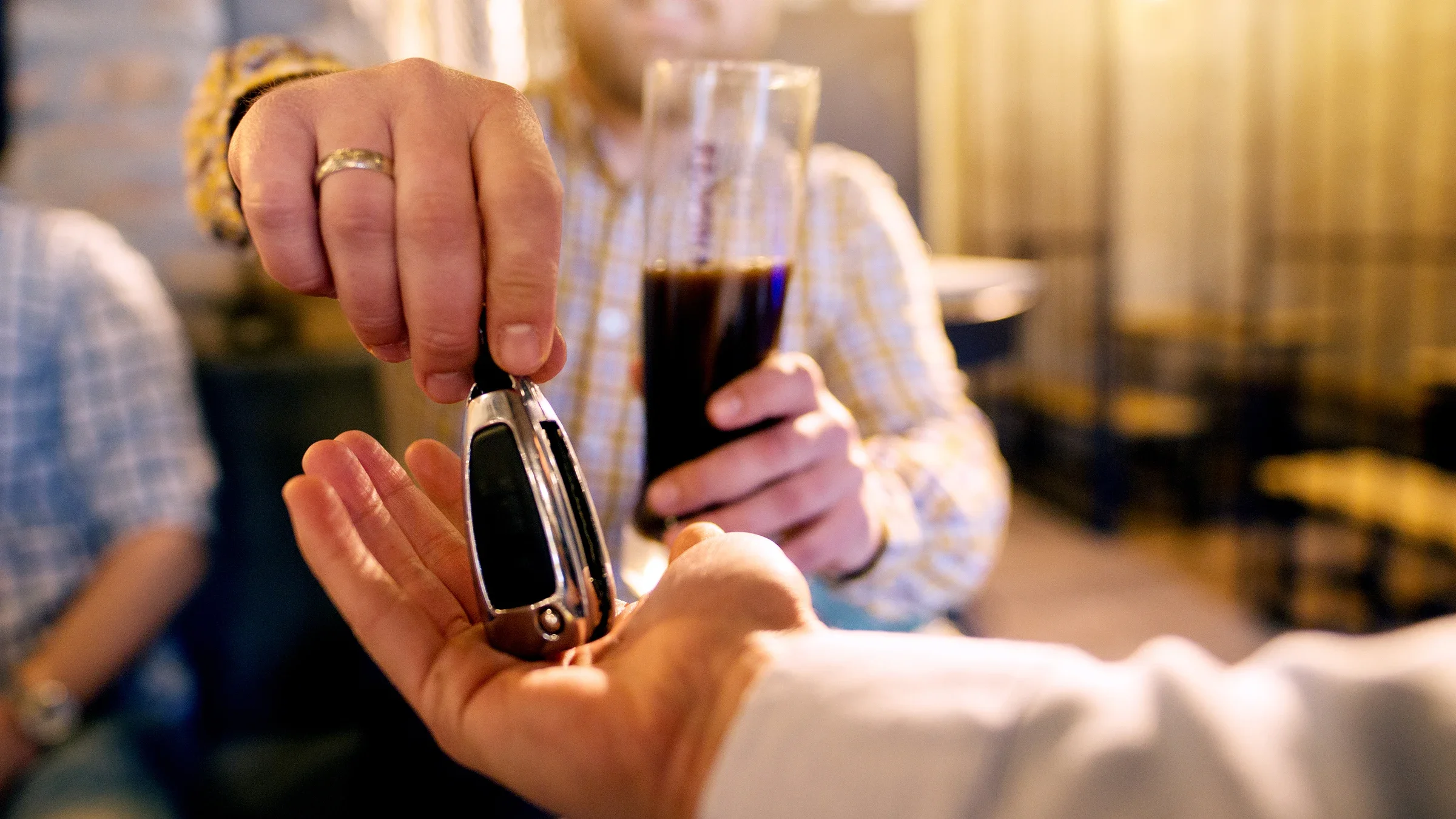 Close-up of a person handing their friend their car keys. They have been drinking and have a beer in their hand.
dusanpetkovic/iStock via Getty Images
