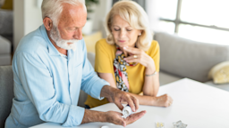 Senior woman helping her husband take his medication at home.
DjelicS/E+ via Getty Image
