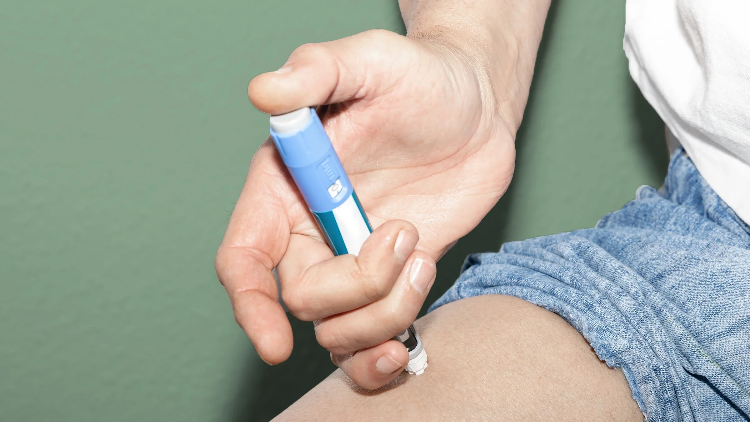 An Ozempic injection, in close-up, goes into a leg.