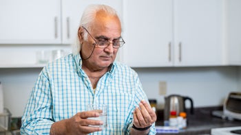 Simvastatin: man taking pill with water 1061711860 (1)