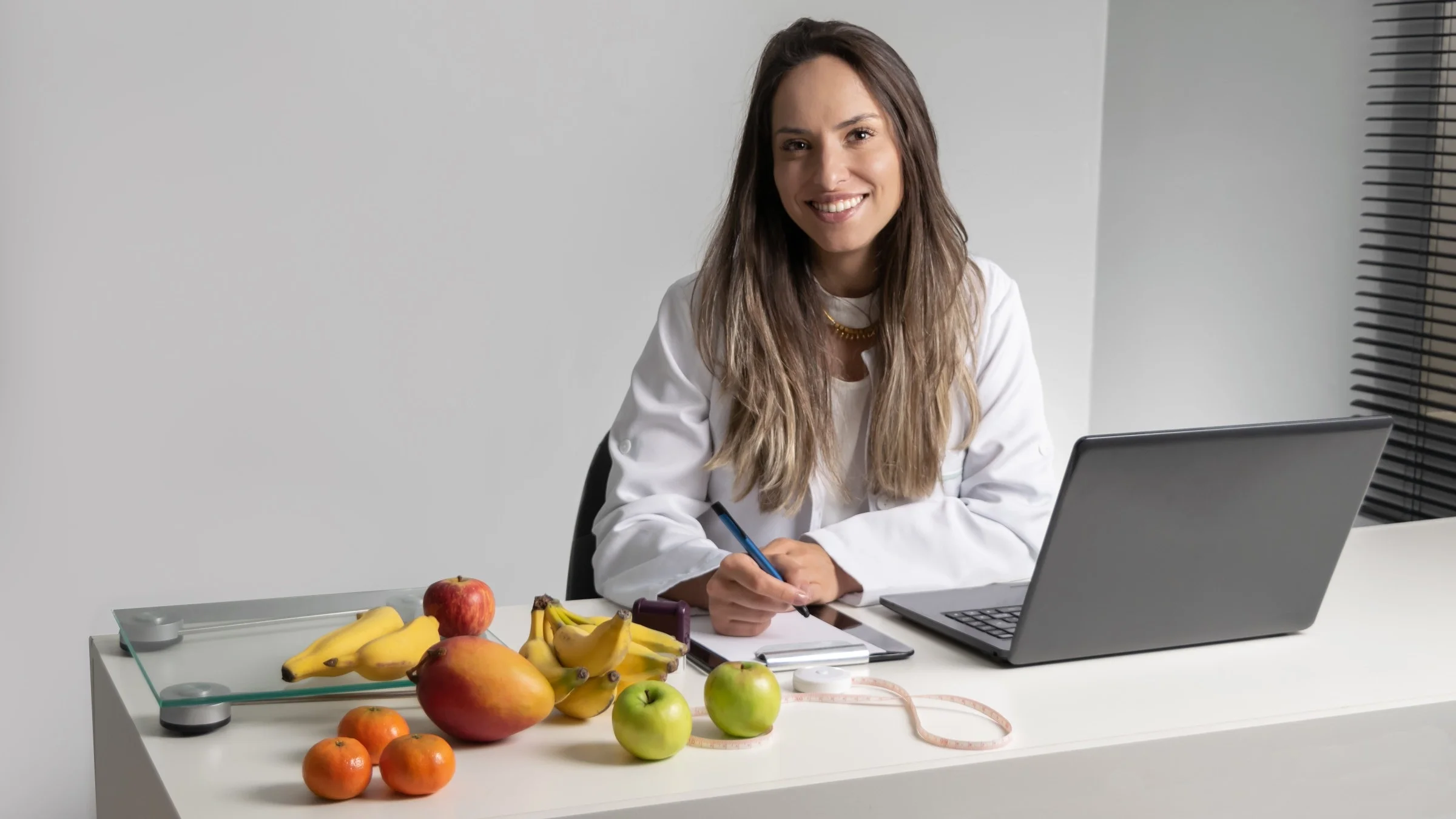 Portrait of a nutritionist at her desk with fresh fruits surrounding her.