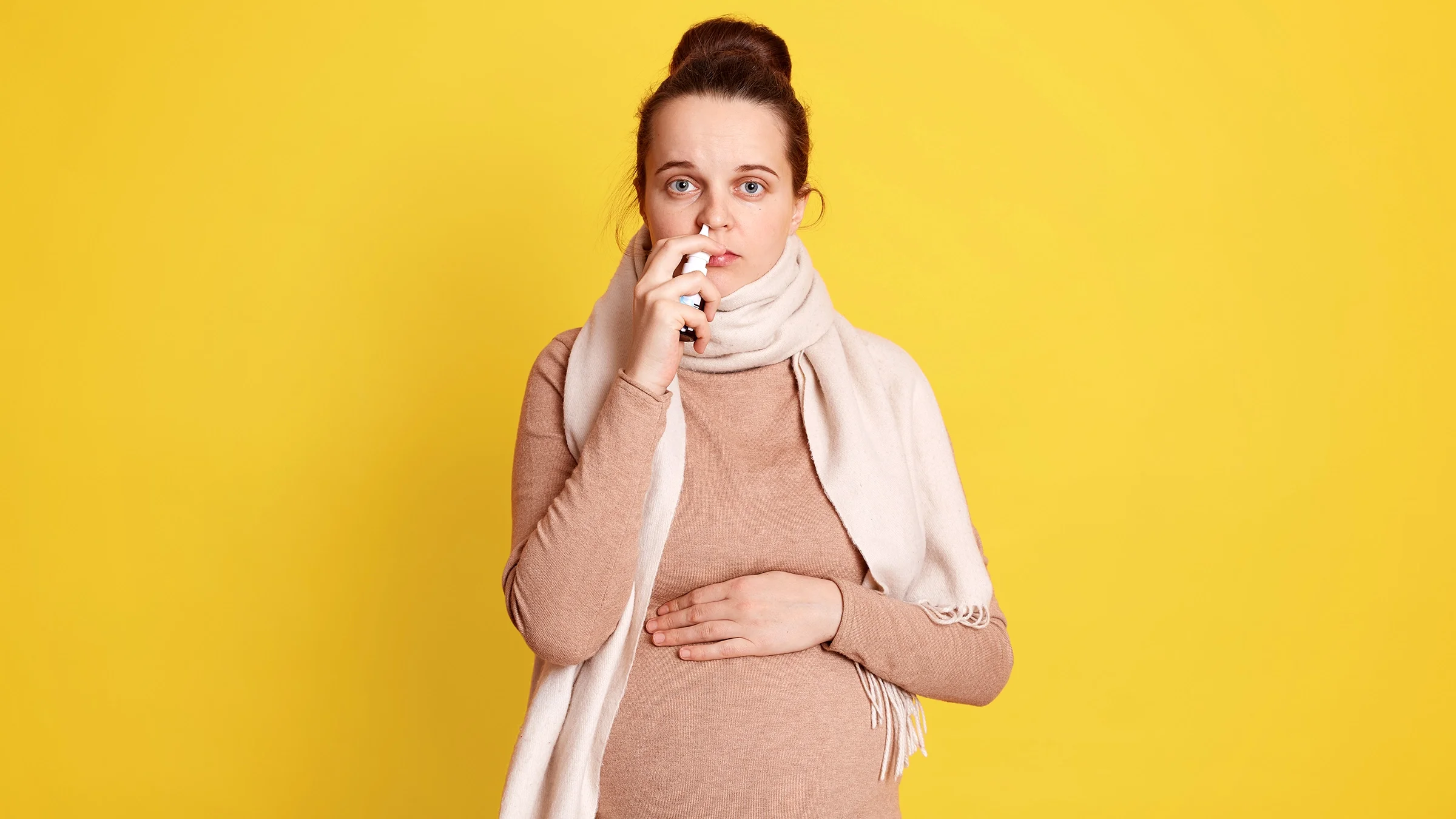 A pregnant woman using a nasal spray.