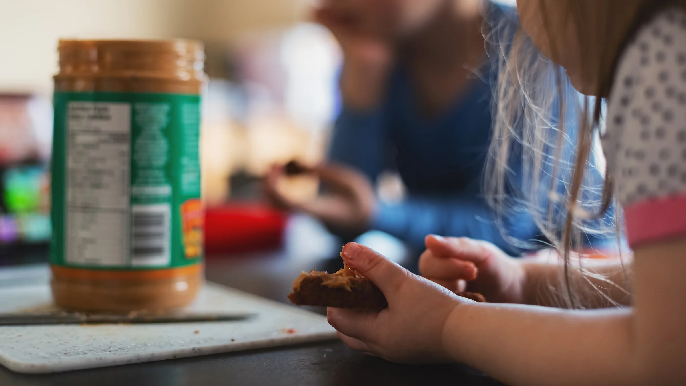 Close-up of a kid eating peanut butter at the dining table.