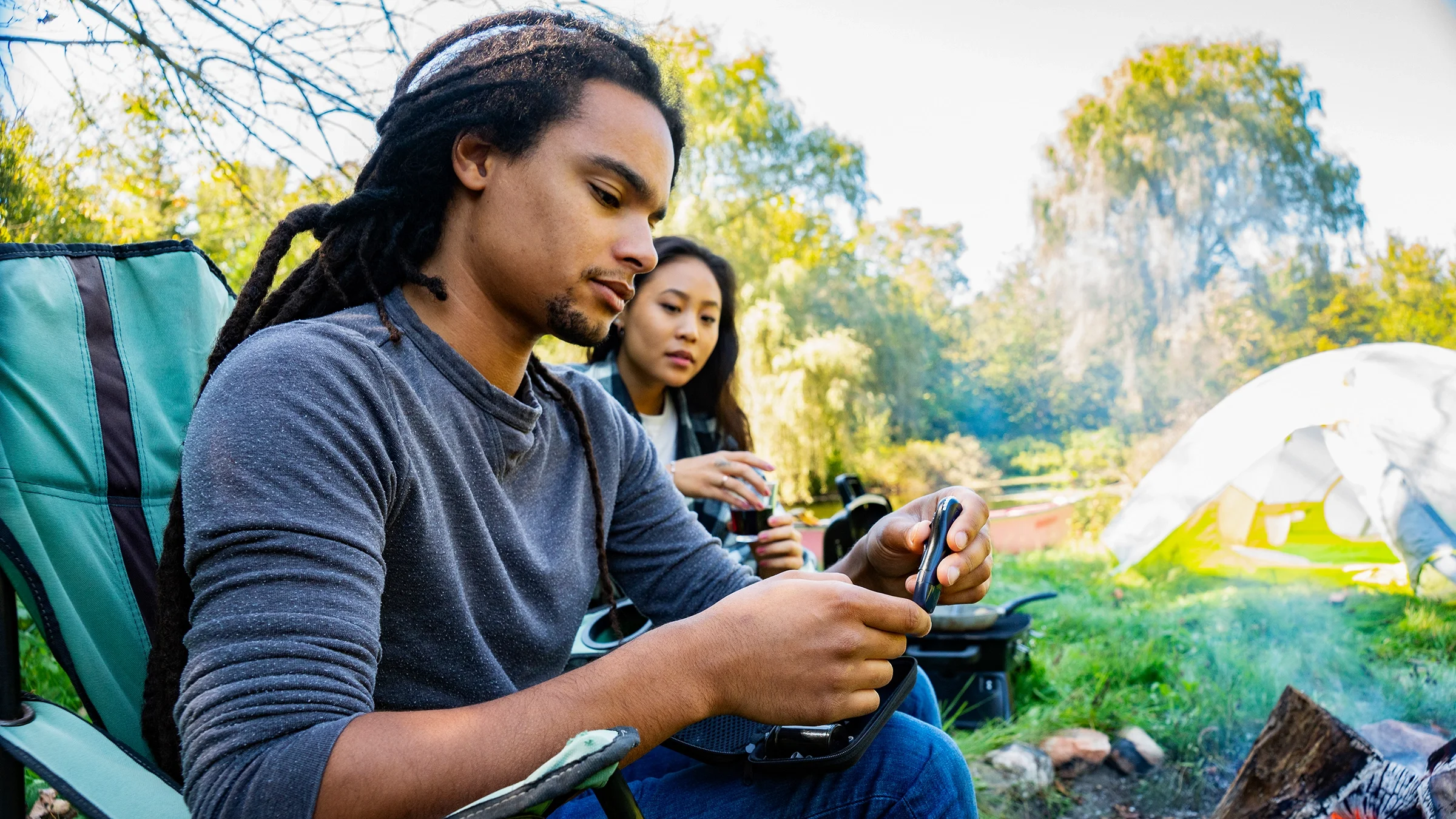 Man checks his blood sugar levels with glucometer while camping with partner.