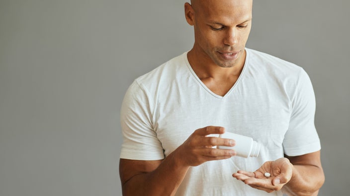 Man in white t-shirt takes pill. 