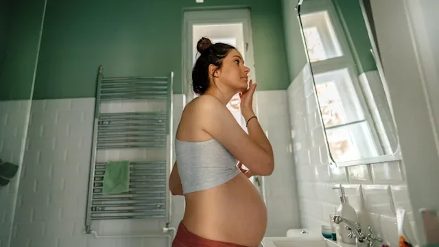 pregnancy: pregnant woman applying face mosturizer 1252901051