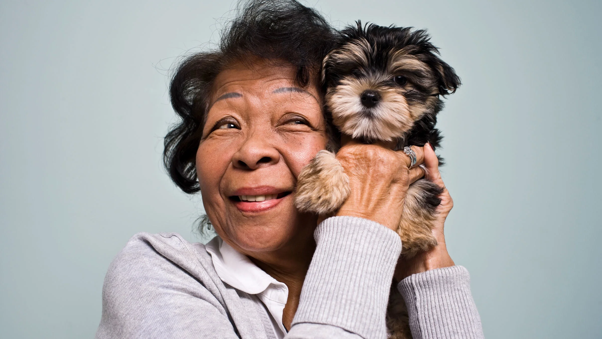 Older woman poses with puppy.