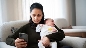 weight loss: mother holding baby and looking at phone 1492073386
