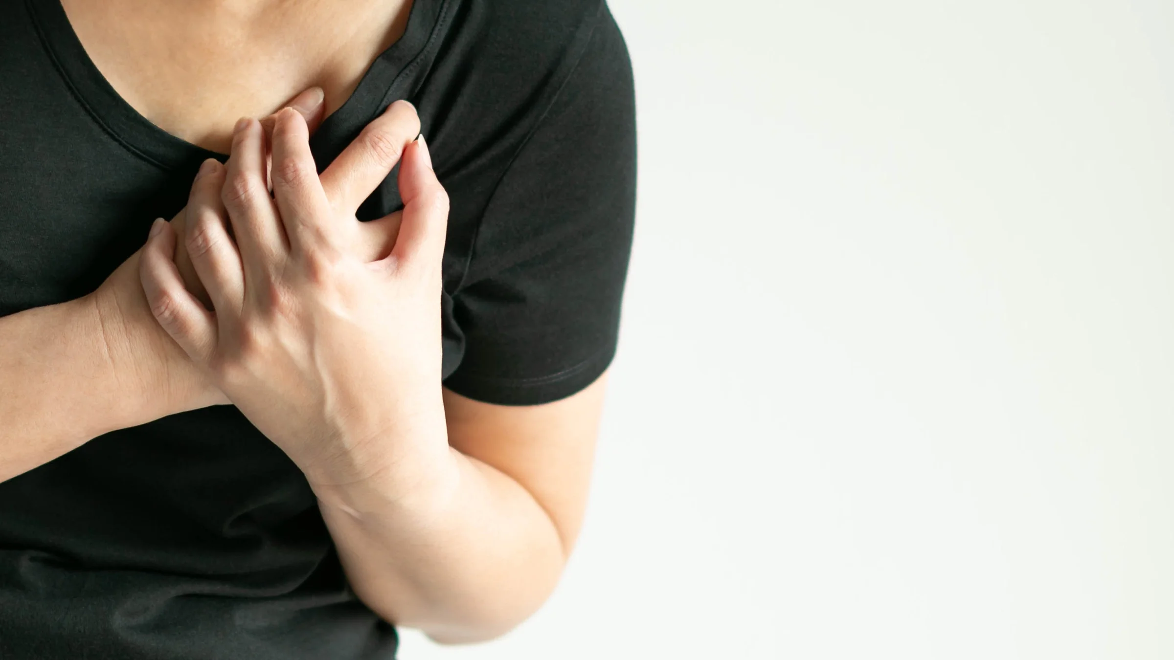 Cropped shot of a woman clutching her heart and chest in pain.
