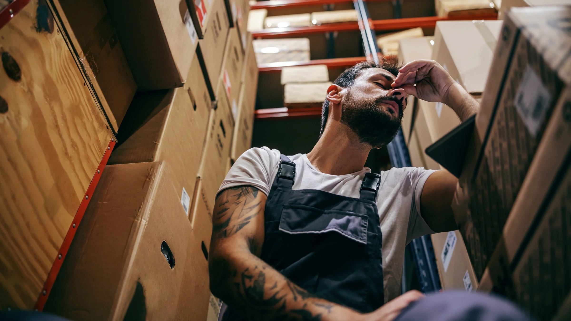 A worker stressed out in a storage room.