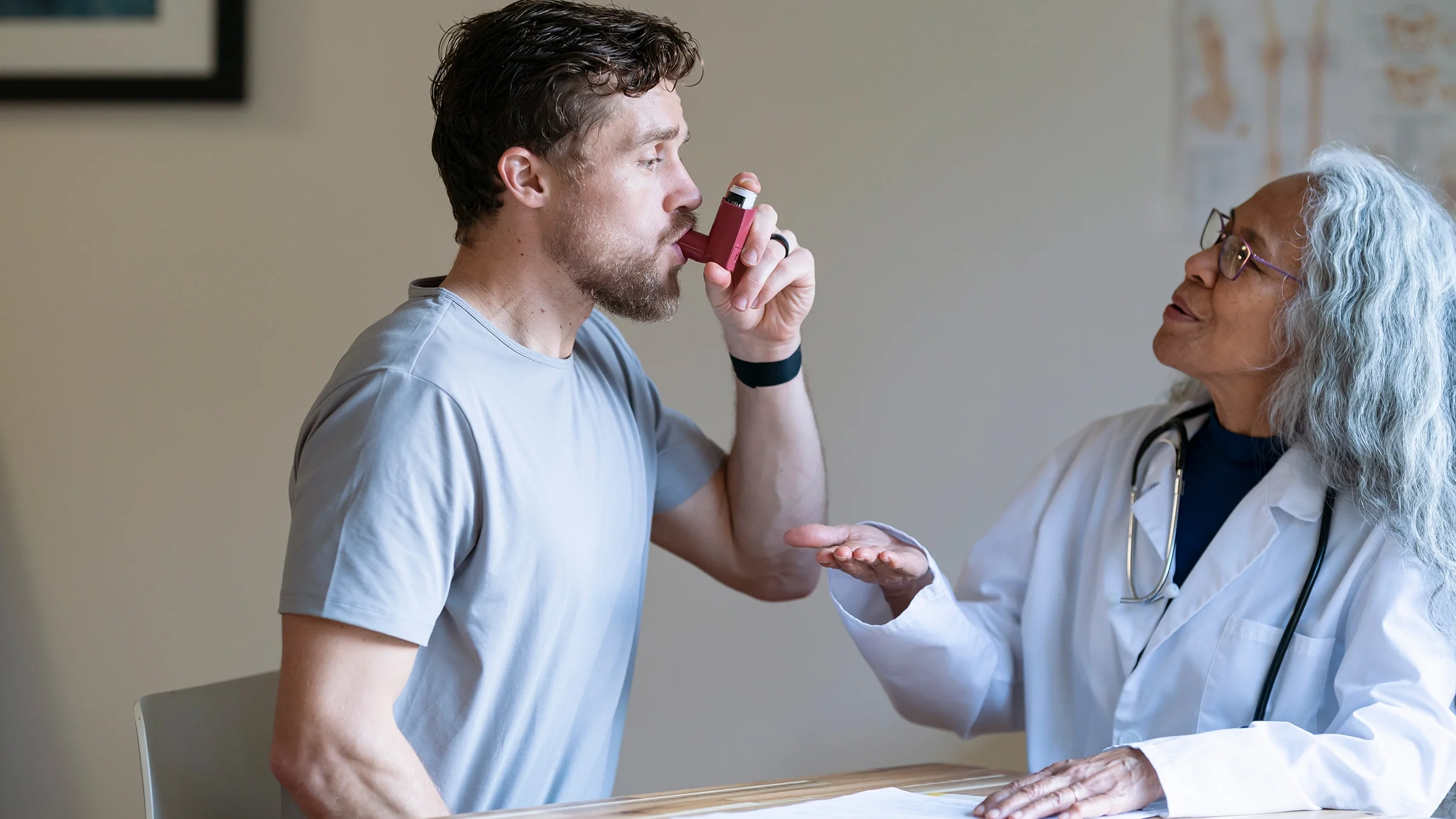 A man is in a medical consultation learning how to use an asthma inhaler.